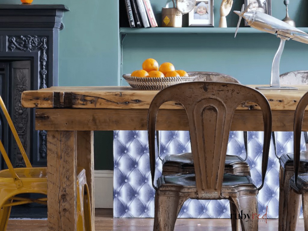 Farmhouse kitchen-dining space featuring rustic wooden table, metal chairs, teal backdrop and vintage fireplace — rustic dining room decor ideas.