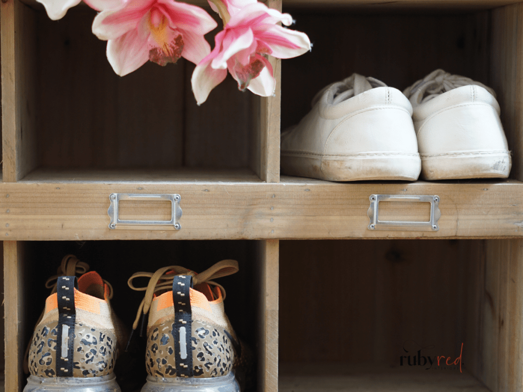 Farmhouse shoe storage cubby with wood shelves, organised footwear, and soft floral accents.
